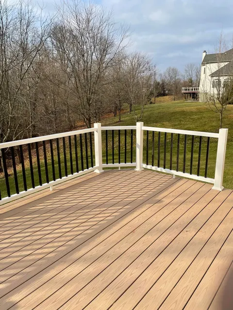 Composite deck with white railing and black balusters overlooking a spacious backyard