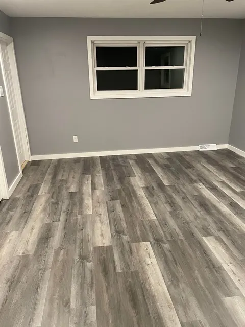 Gray luxury vinyl plank flooring installed in freshly painted room with new white trim