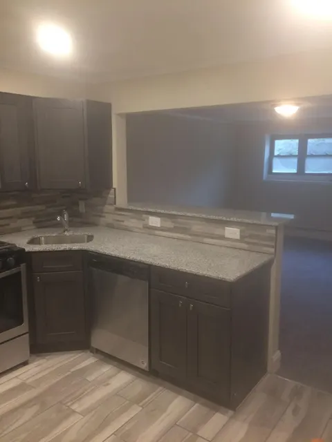 Remodeled kitchen with dark shaker cabinets, granite countertops, and breakfast bar pass-through