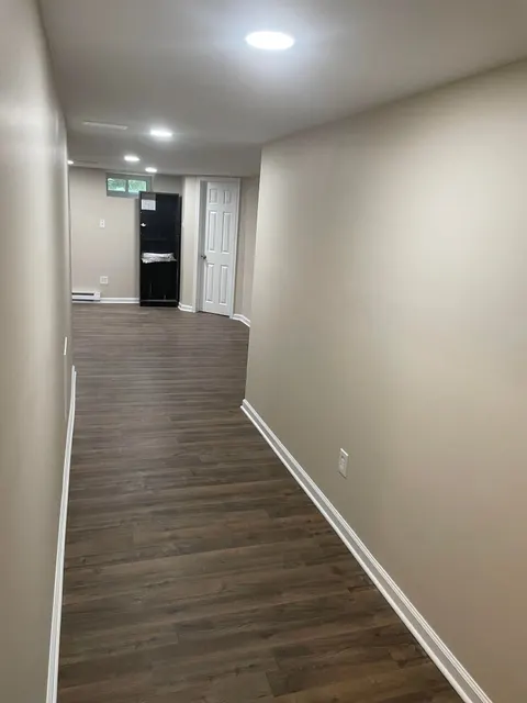 Finished basement hallway with dark wood-look vinyl plank flooring and recessed lighting