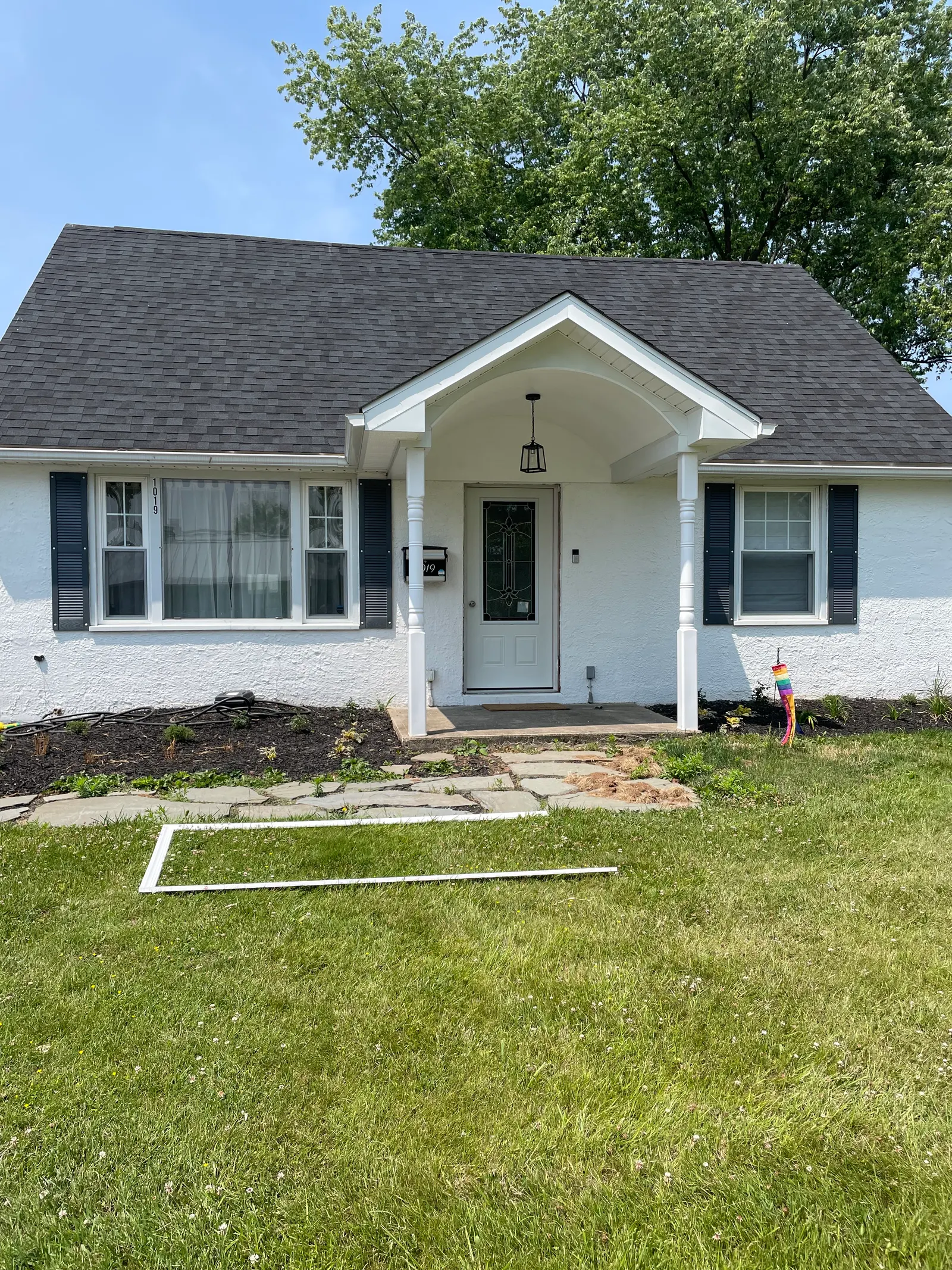 Renovated home exterior with new roof, arched front portico, columns, and fresh landscaping