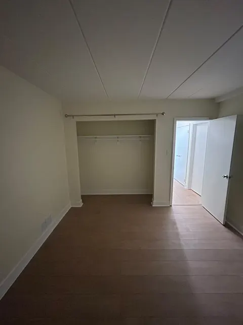 Bedroom with new luxury vinyl plank flooring, white baseboards and an open closet with new shelving