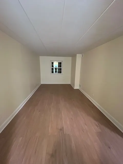 Long room with new luxury vinyl plank flooring, white baseboards and freshly painted walls
