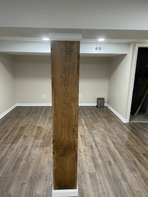 Finished living area with stained wood accent beam and wide-plank vinyl flooring