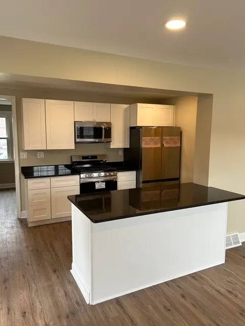 Kitchen remodel with white shaker cabinets, dark granite island, and new stainless appliances