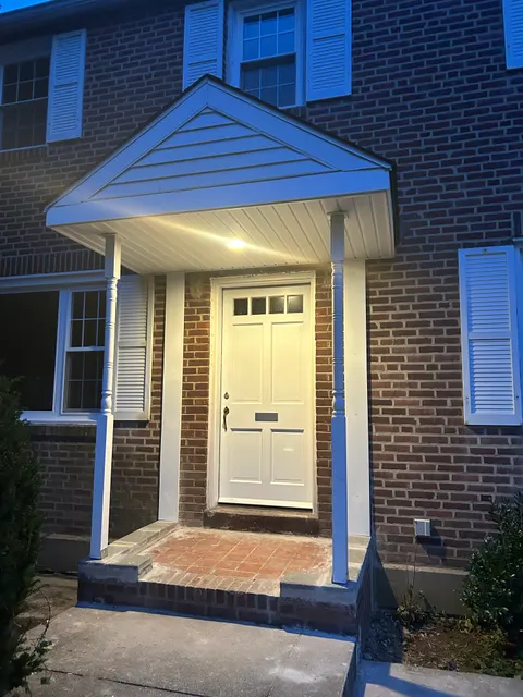 New front entry portico with white columns and gable roof lit at dusk