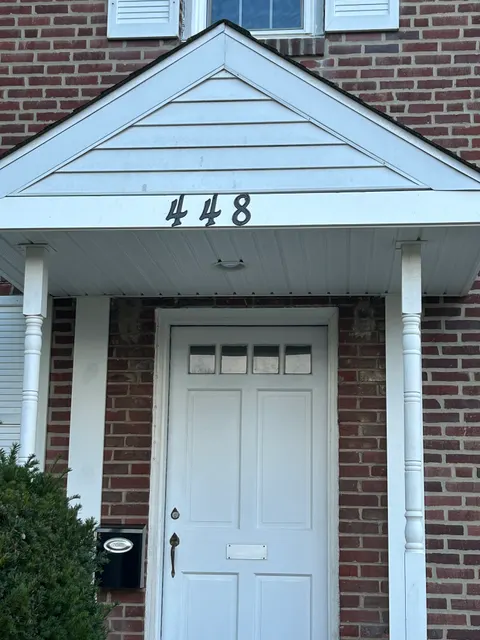 Front entry portico with paneled gable, turned columns, and brick facade