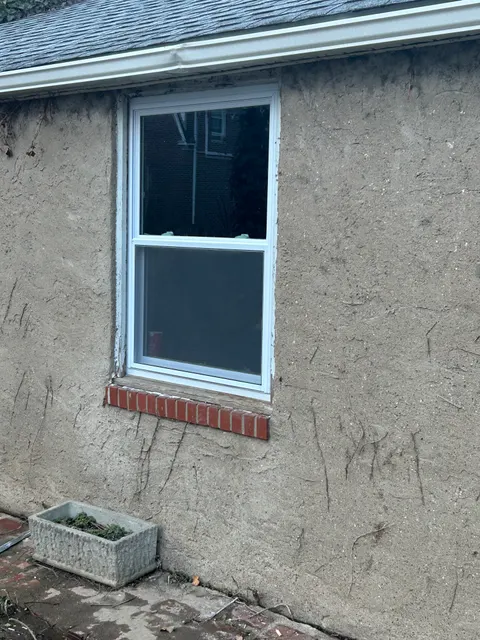 Replacement vinyl sliding window installed in stucco wall with brick sill