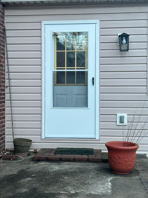 New white storm door installed on rear entry with vertical siding