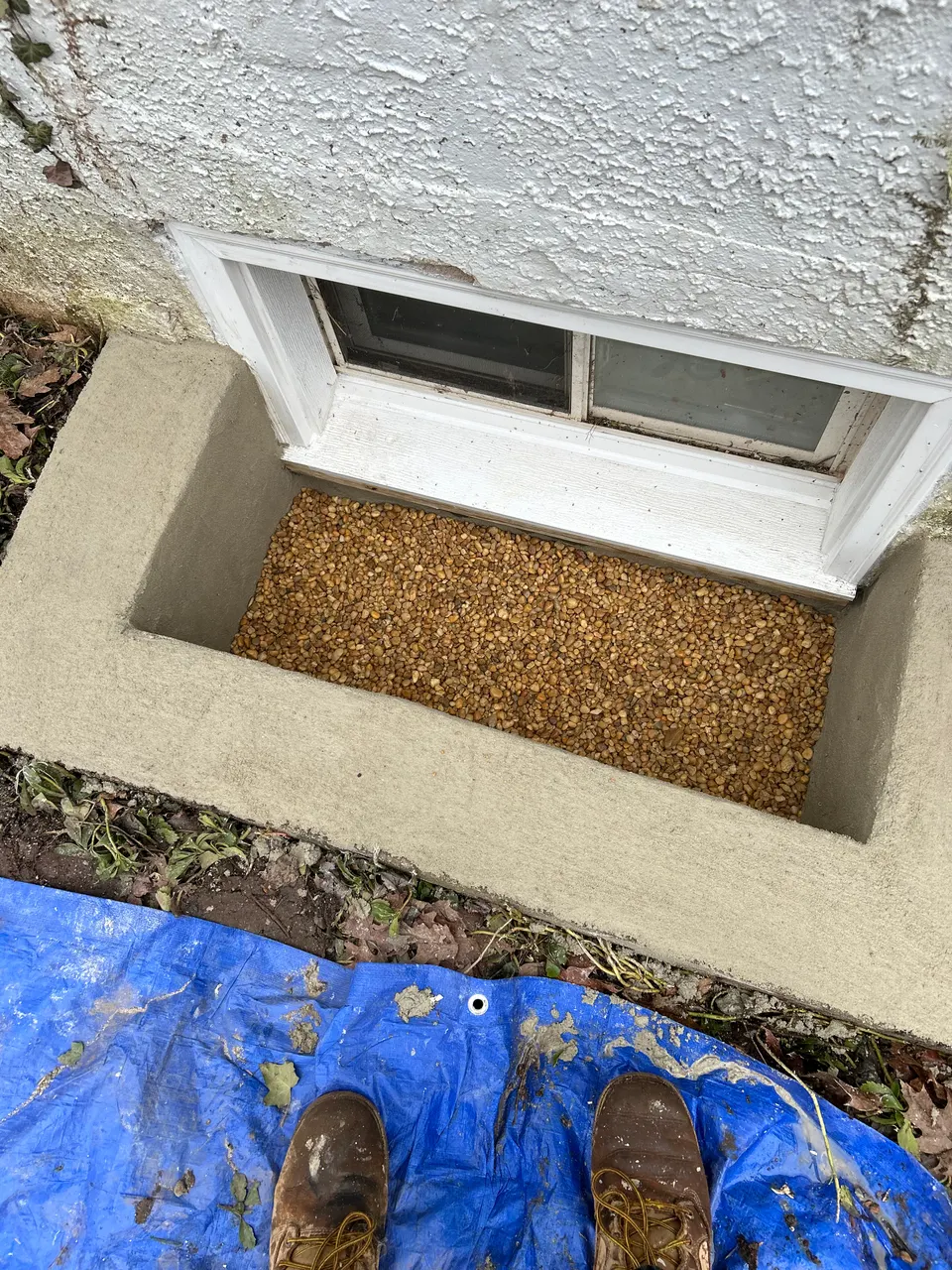 New concrete basement window well with gravel drainage below replacement window