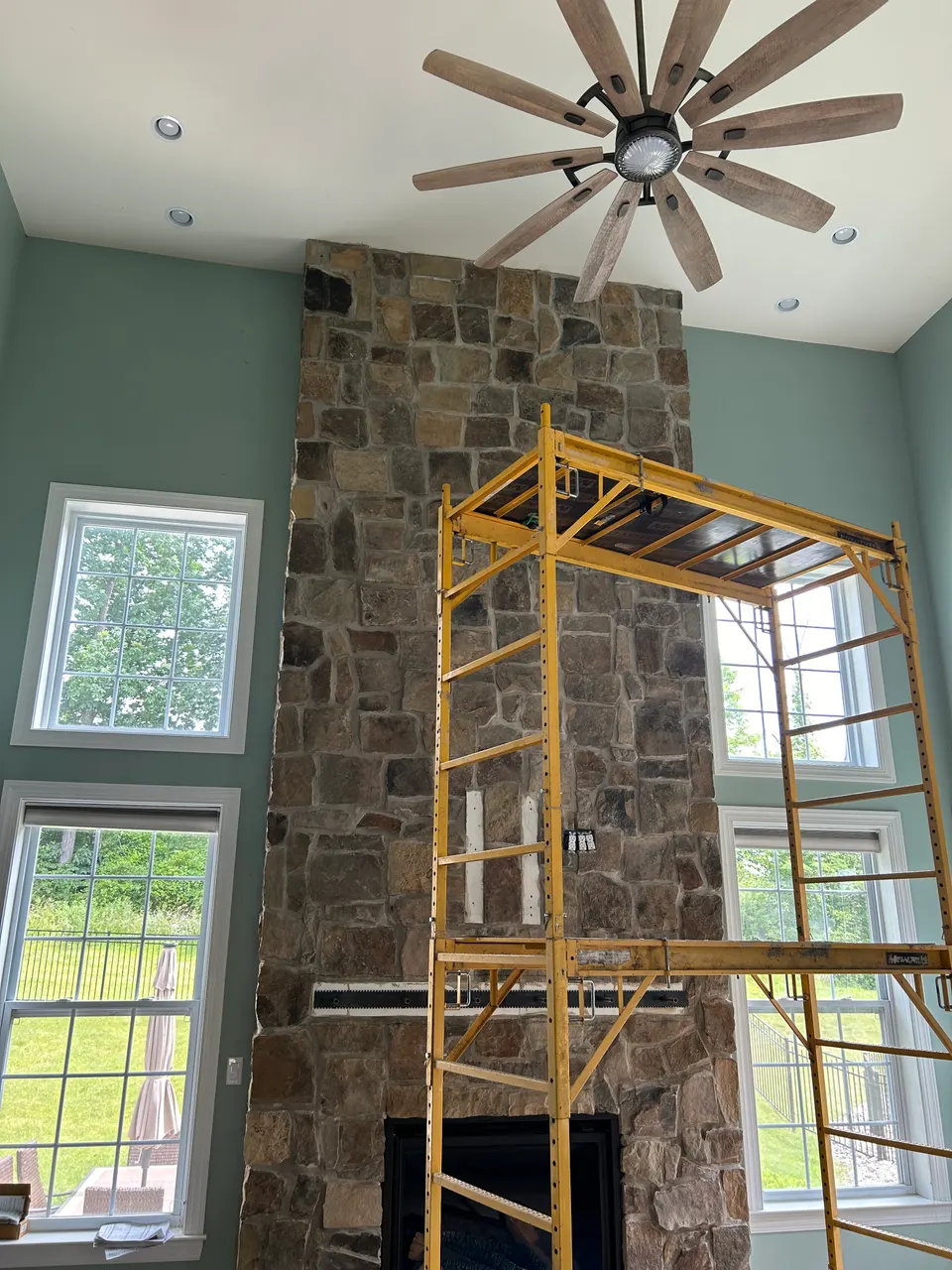 Floor-to-ceiling stacked stone fireplace installation in two-story great room