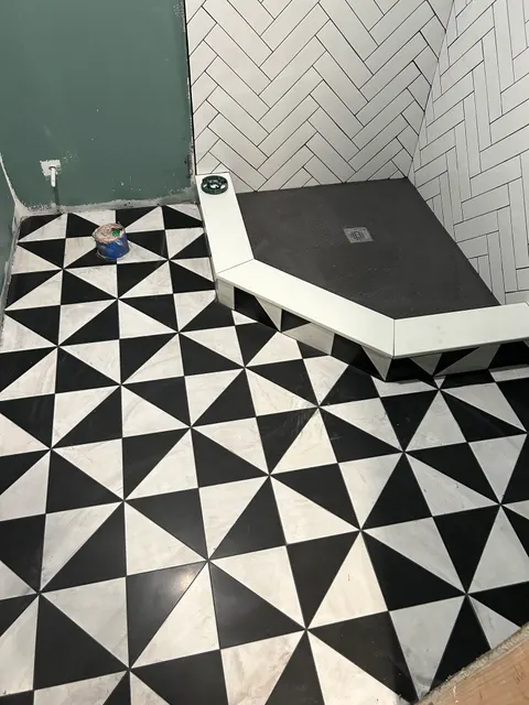 Bathroom remodel with black and white geometric floor and herringbone tile shower