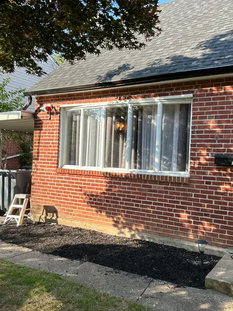 New seamless gutters and downspout installed along roofline of brick home