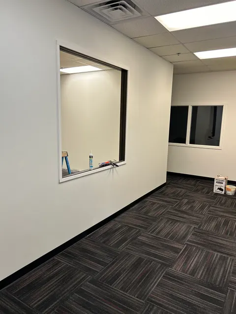 Completed drywall partition wall with interior pass-through window in office renovation