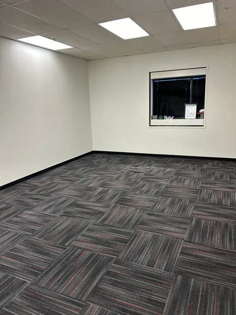 Finished office renovation with new partition wall, interior window, and carpet tile flooring