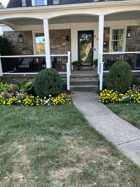 Inviting front porch with white columns, railings, and landscaped stone walkway