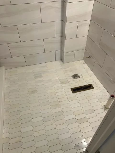 Tiled tub surround with display ledge and elongated hexagon marble accent wall