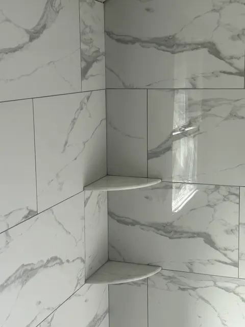 Marble tile shower bench detail with curved built-in corner shelves