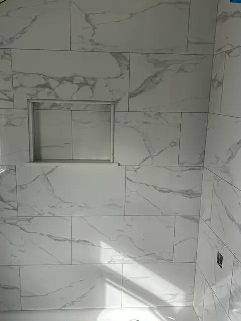 Fully tiled marble shower with trimmed storage niche awaiting fixture installation