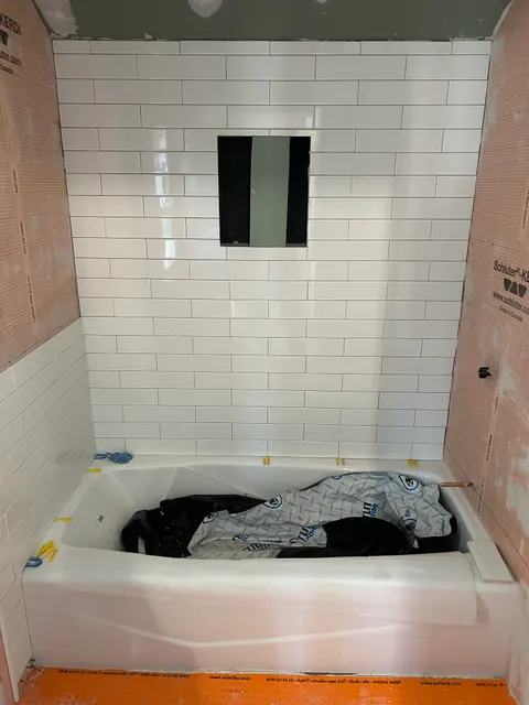 White subway tile tub surround installation over waterproofing membrane