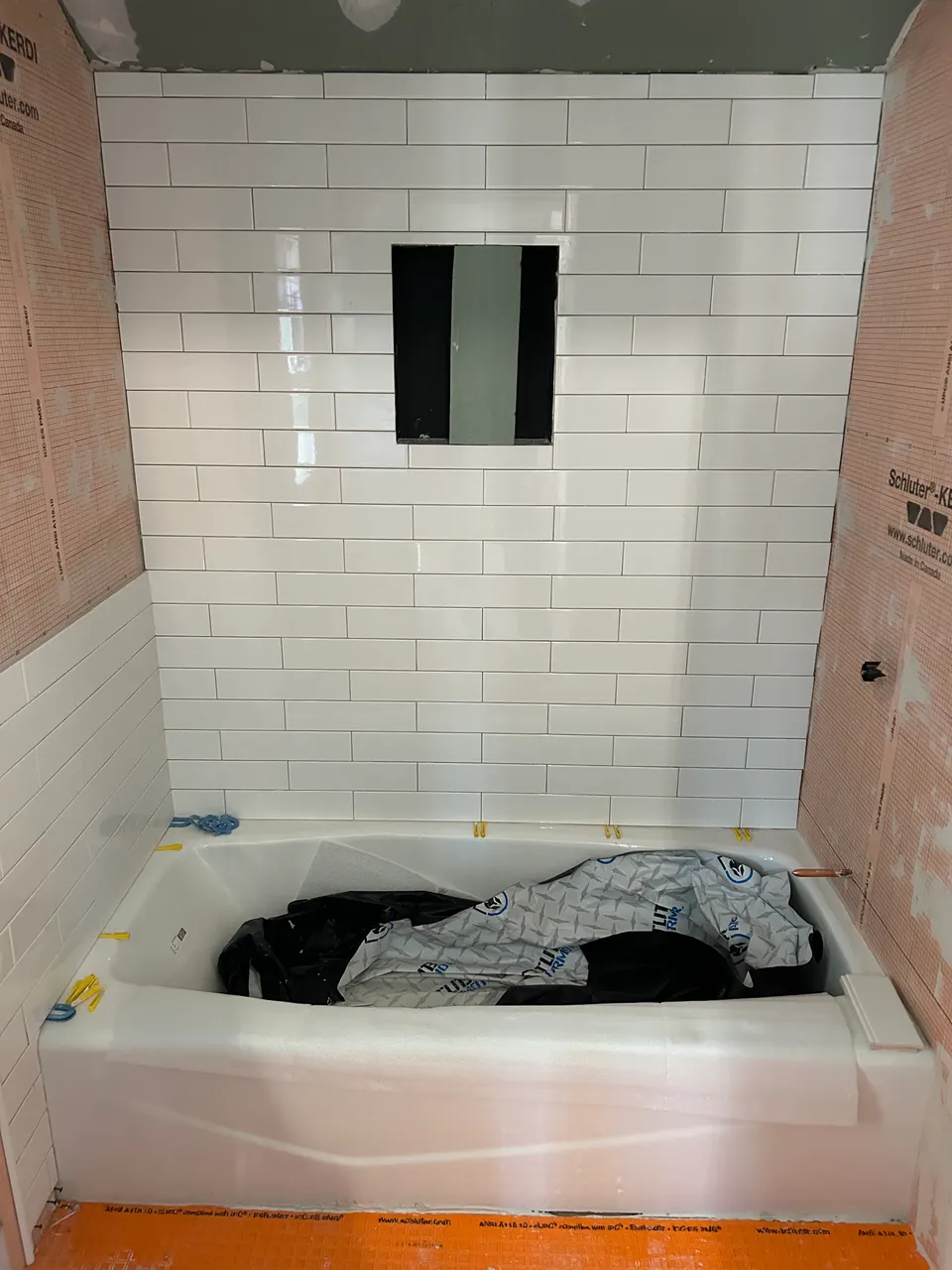 White subway tile tub surround installation over waterproofing membrane