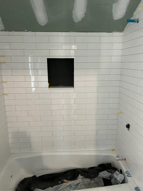 White subway tile tub and shower surround with recessed niche during install