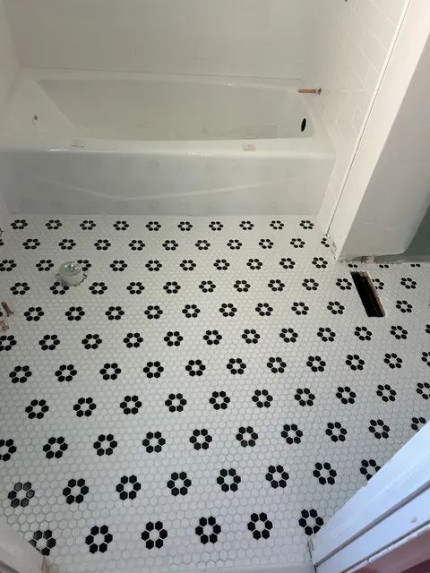 Classic black and white hexagon mosaic bathroom floor beside new tub