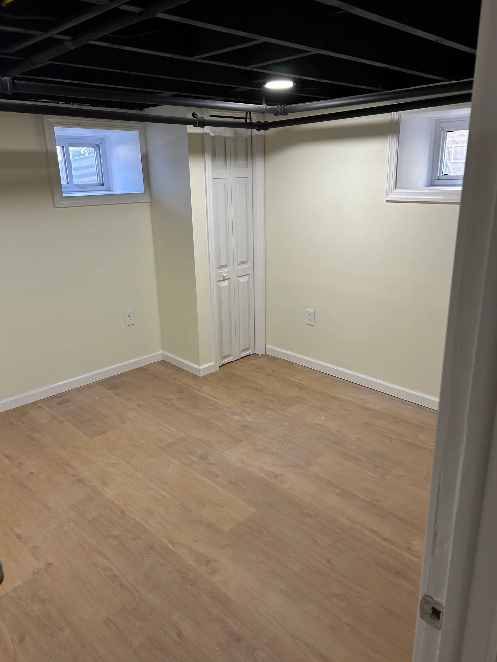 Finished basement bedroom with new luxury vinyl plank flooring and white closet doors