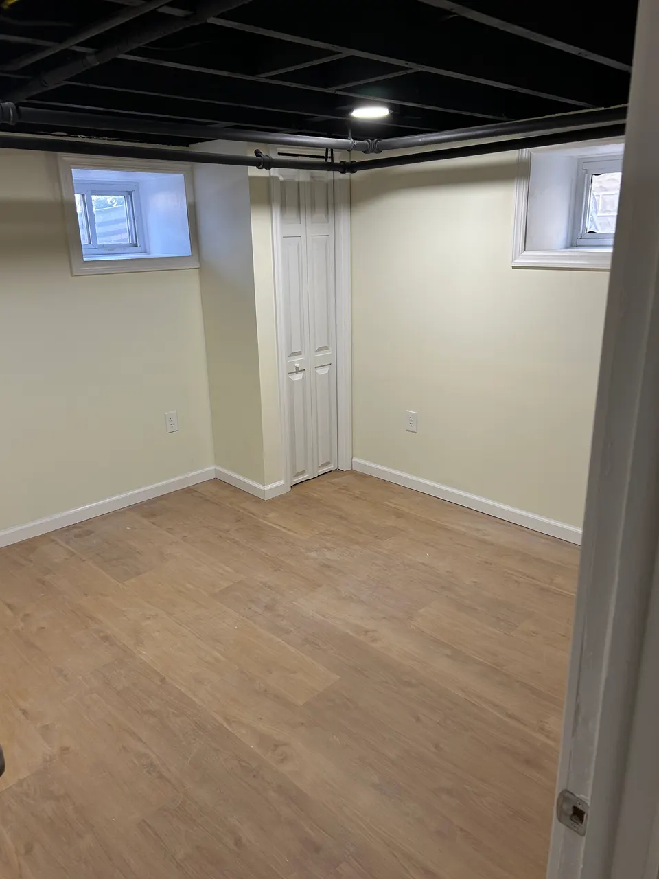 Finished basement bedroom with new luxury vinyl plank flooring and white closet doors