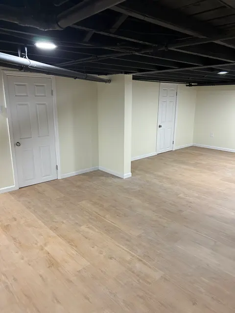 Finished basement hallway with new vinyl plank flooring and white six-panel doors