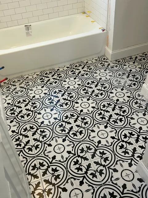 New black and white patterned ceramic tile floor beside freshly tiled tub surround