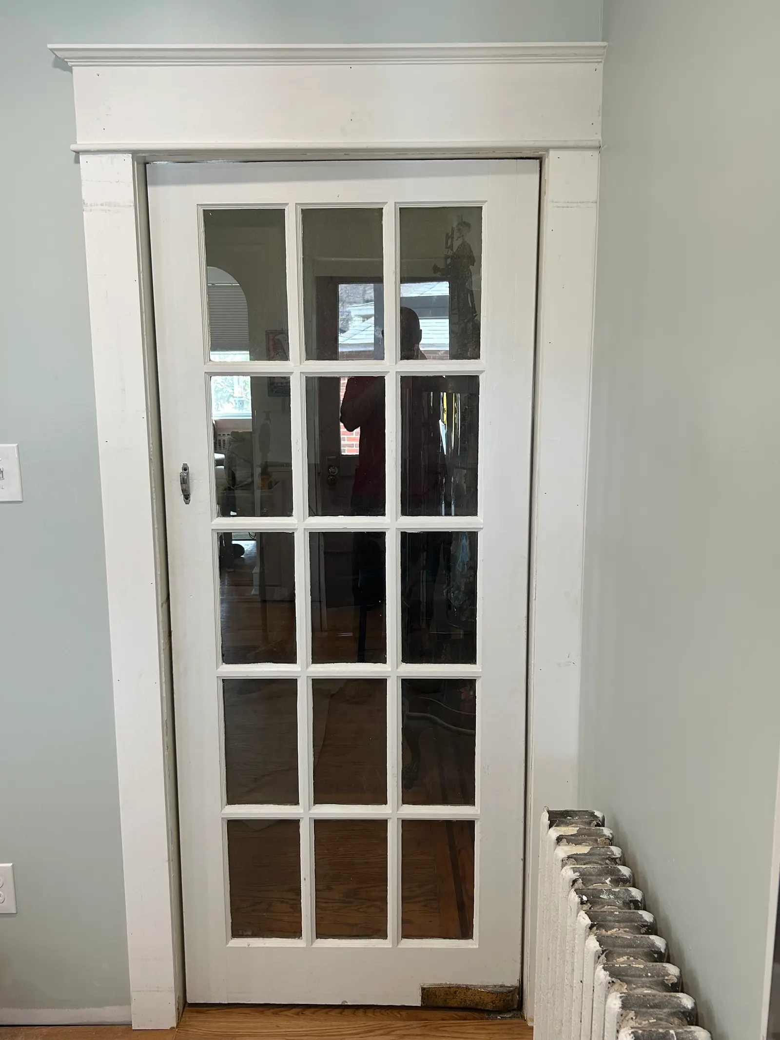 White fifteen-lite glass French door with fresh trim installed between kitchen and dining room