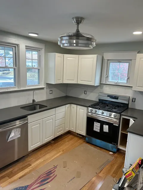 Kitchen remodel nearing completion with white cabinets, quartz counters, and stainless appliances