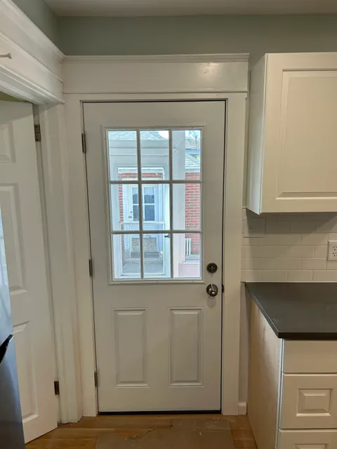 New nine-lite back entry door installed beside white cabinetry in remodeled kitchen