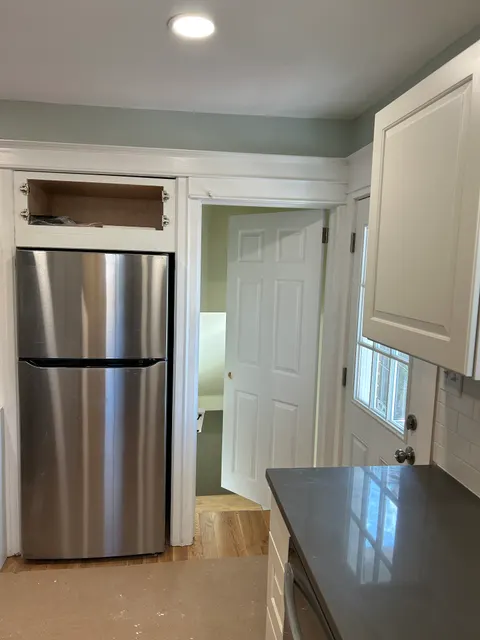 Remodeled kitchen entry with stainless refrigerator and freshly painted mudroom beyond