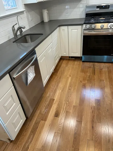 Kitchen counter run with quartz surfaces, subway tile backsplash, and stainless dishwasher