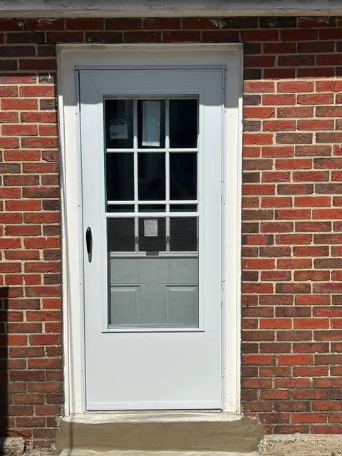 New entry door and storm door installed in brick facade with repaired concrete sill