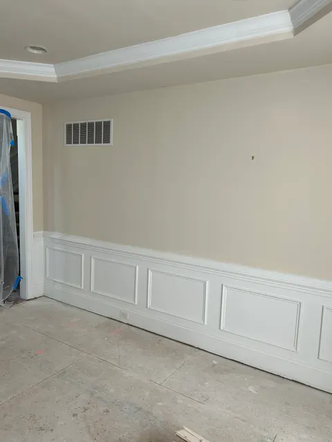 Freshly painted room with custom white wainscoting panels prepared for new flooring installation