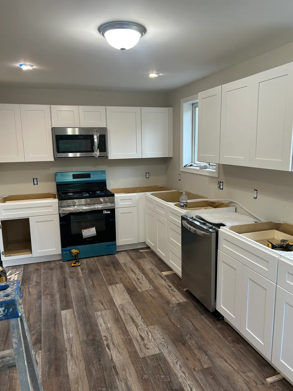 Kitchen remodel with white shaker cabinets, skylight, and rustic wood-look plank flooring underway