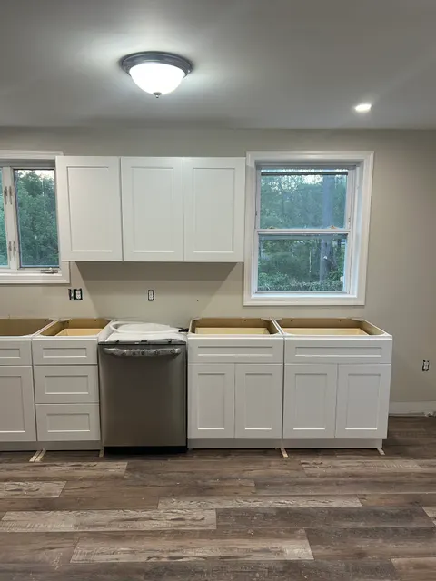 Floor-to-ceiling pantry cabinets and dishwasher installation in white shaker kitchen remodel