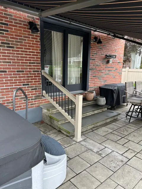 Finished porch railing in almond vinyl overlooking steps and paver patio