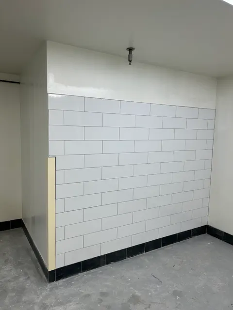 White tile wainscot with a black tile base in a commercial back room renovation