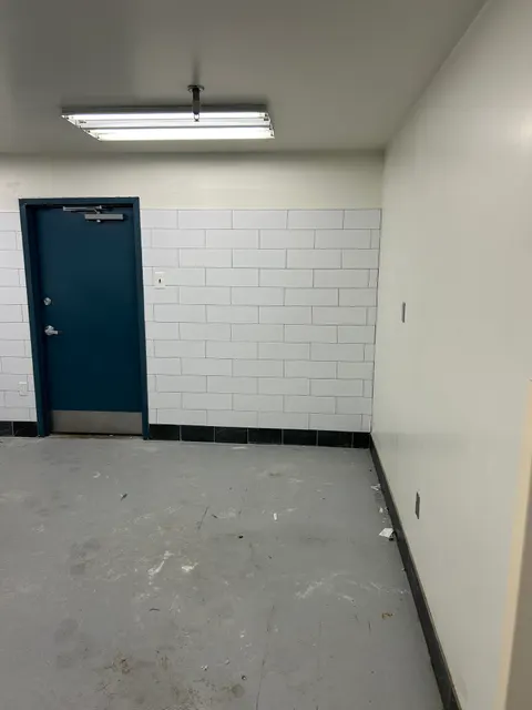 White tile feature wall with black tile accents framing a navy blue commercial door