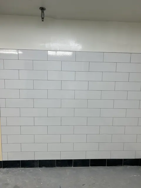White subway tile wall with a black tile accent column, freshly grouted