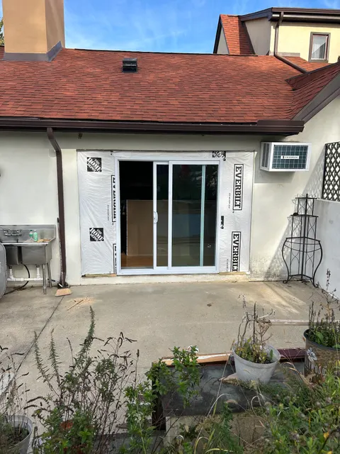 White double-hung replacement window installed with weather barrier ready for siding
