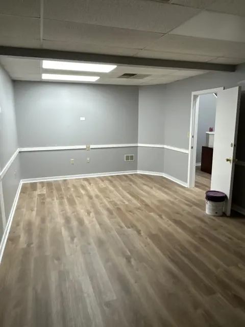 Room finished with gray paint, white chair rail and baseboards, and wood-look luxury vinyl plank flooring
